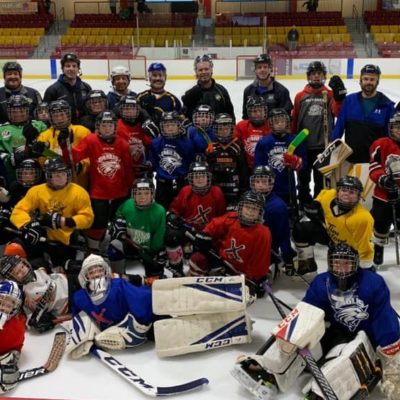Young children who participated in the hockey camp take a team photo with their coaches